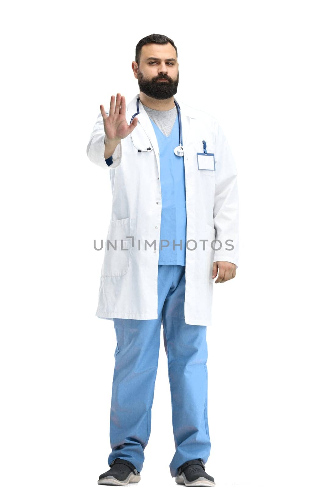 Male doctor, full-length, on a white background, shows a stop sign.