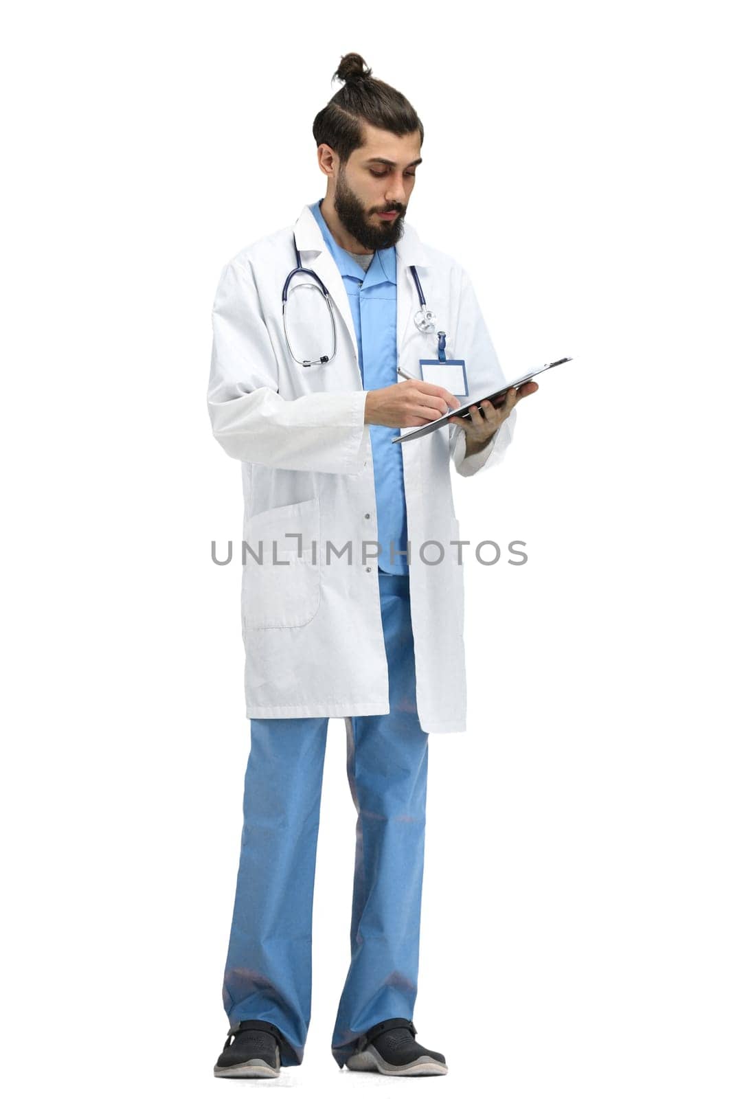 A male doctor, full-length, on a white background, writes.