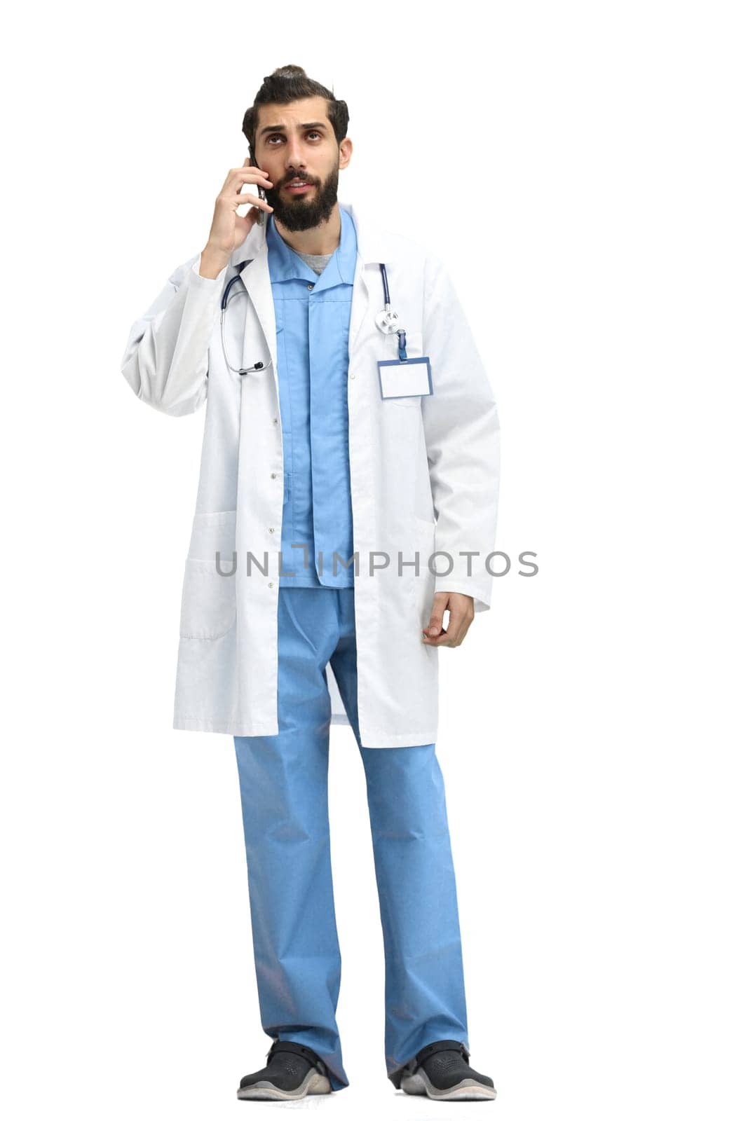 Male doctor, full-length, on a white background, with a phone.