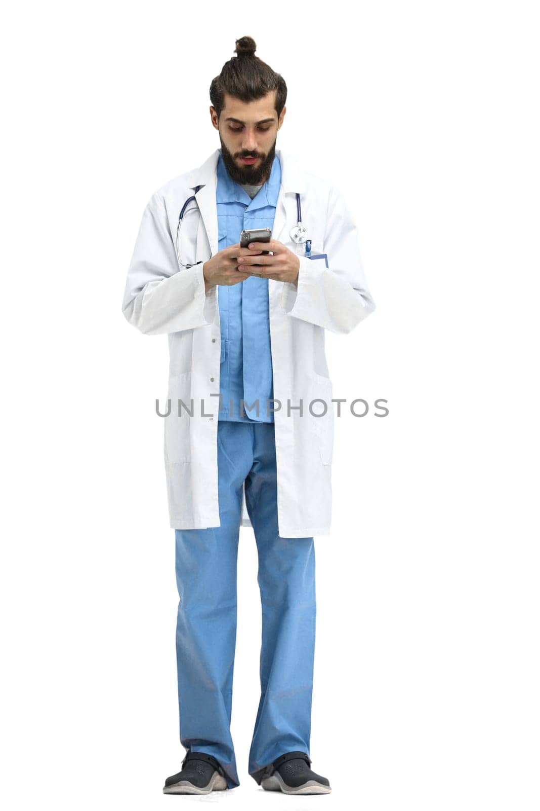 Male doctor, full-length, on a white background, with a phone.