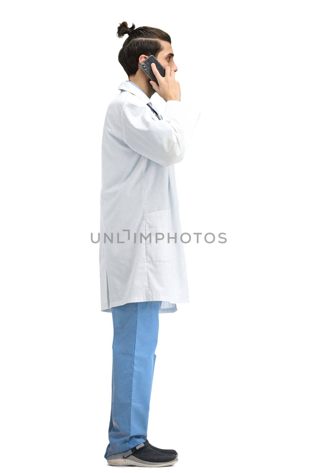 Male doctor, full-length, on a white background, with a phone.