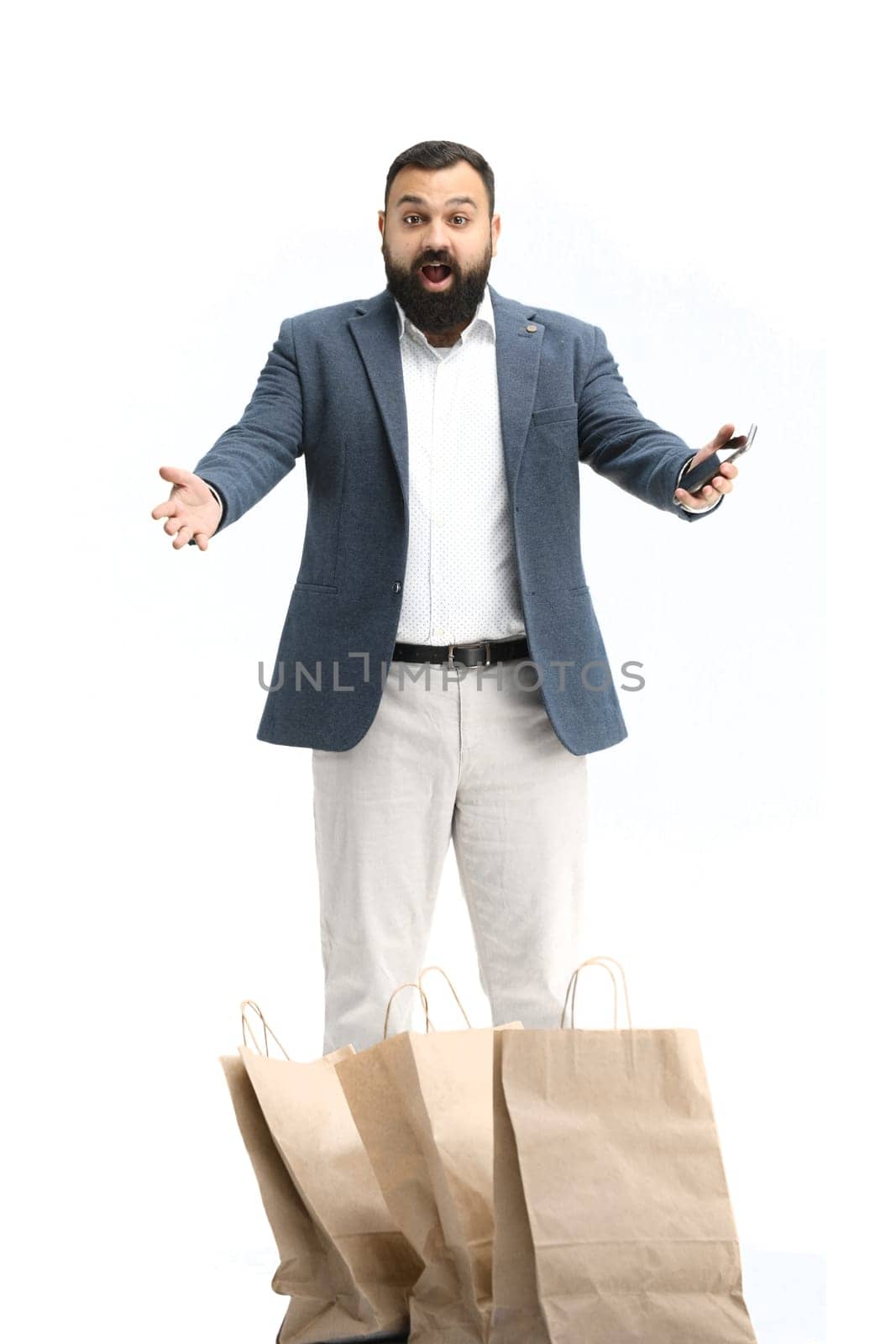 A man, full-length, on a white background, with a phone.
