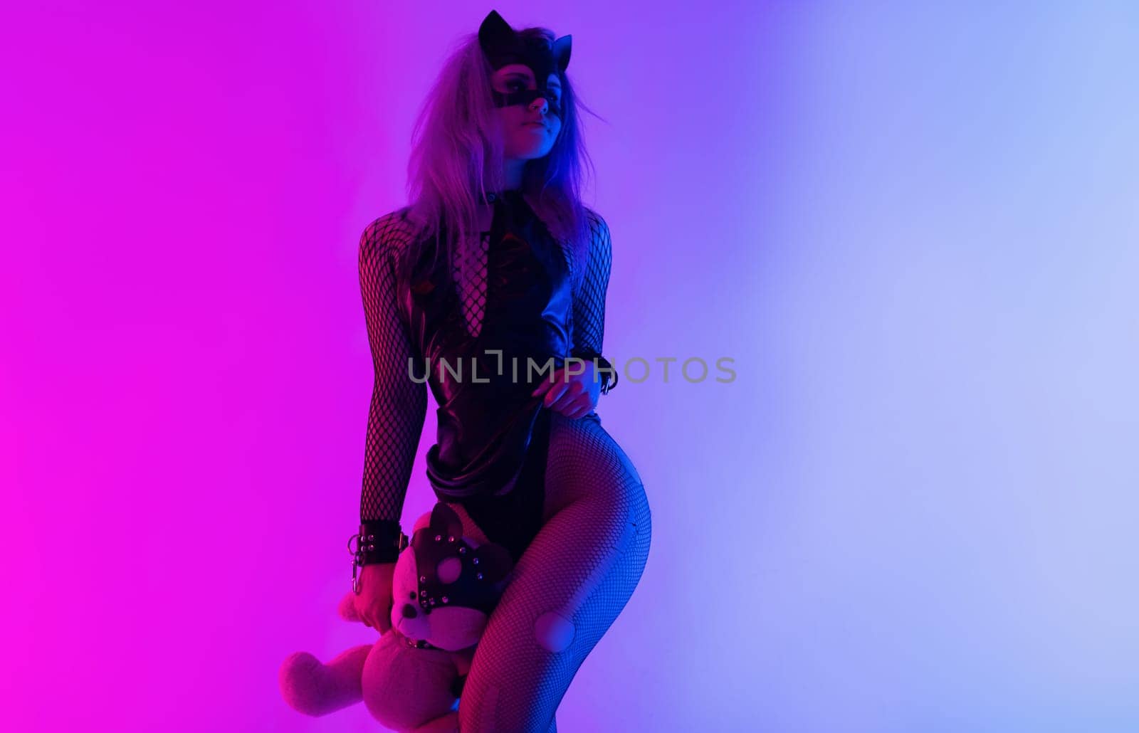 Sexy girl in a latex BDSM mistress dress and a cat mask in neon light on a dark background for a sex game by Rotozey