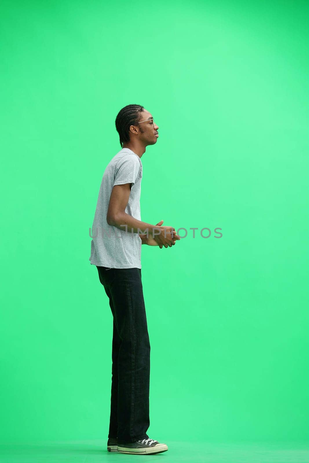 A man in a gray T-shirt, on a green background, in full height.