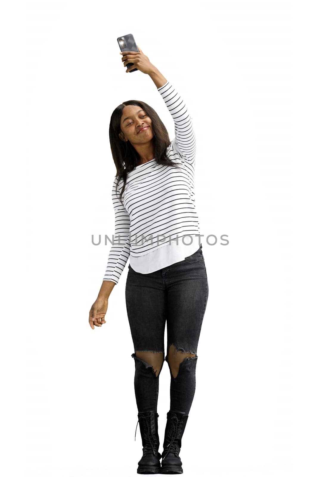 A woman, on a white background, in full height, waving her phone.