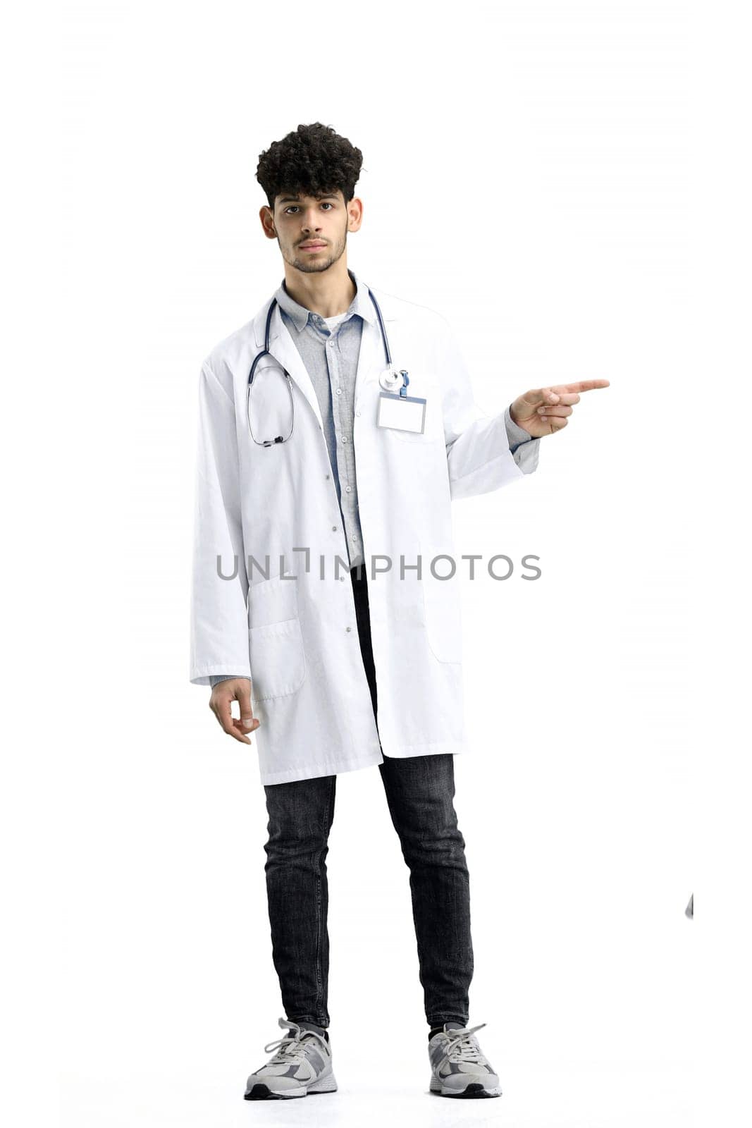 The male doctor, full-length, on a white background, points to the side.