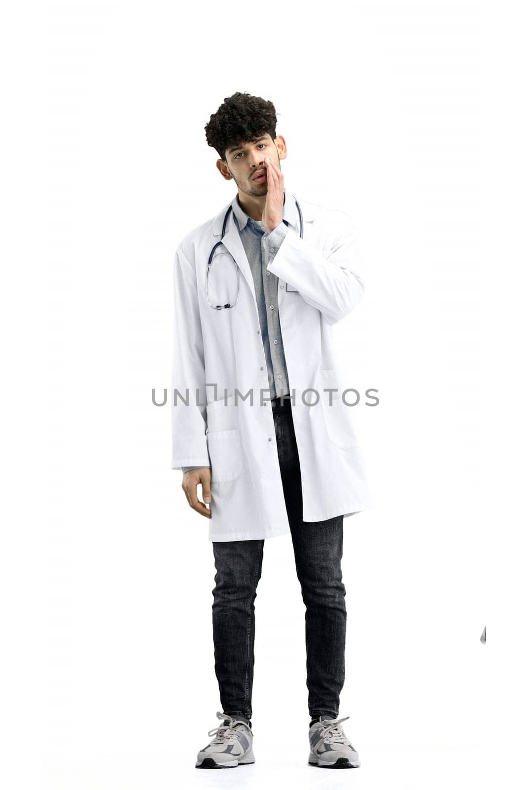 A male doctor, full-length, on a white background, tells a secret.