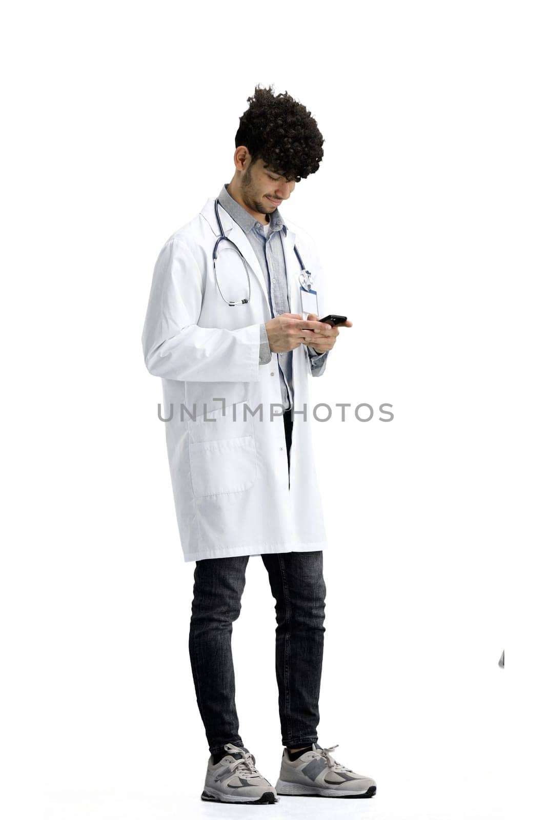 Male doctor, on a white background, full-length, with a phone.