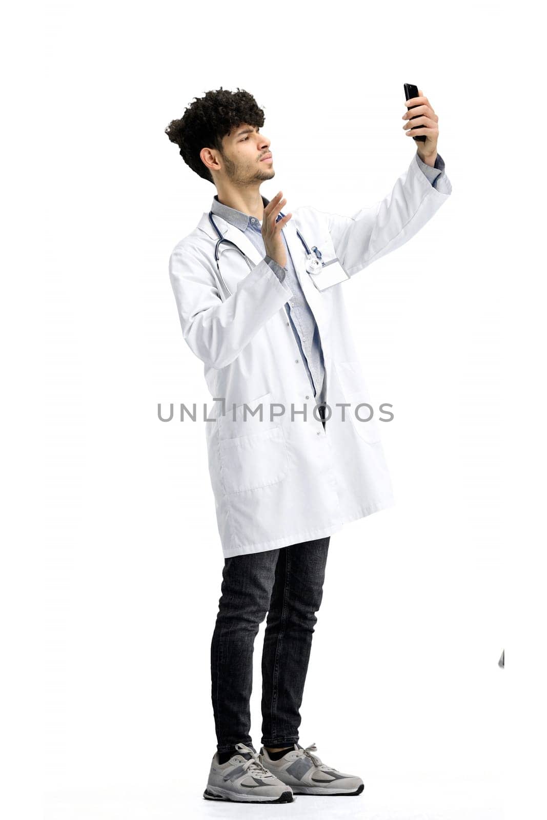 Male doctor, on a white background, full-length, with a phone.