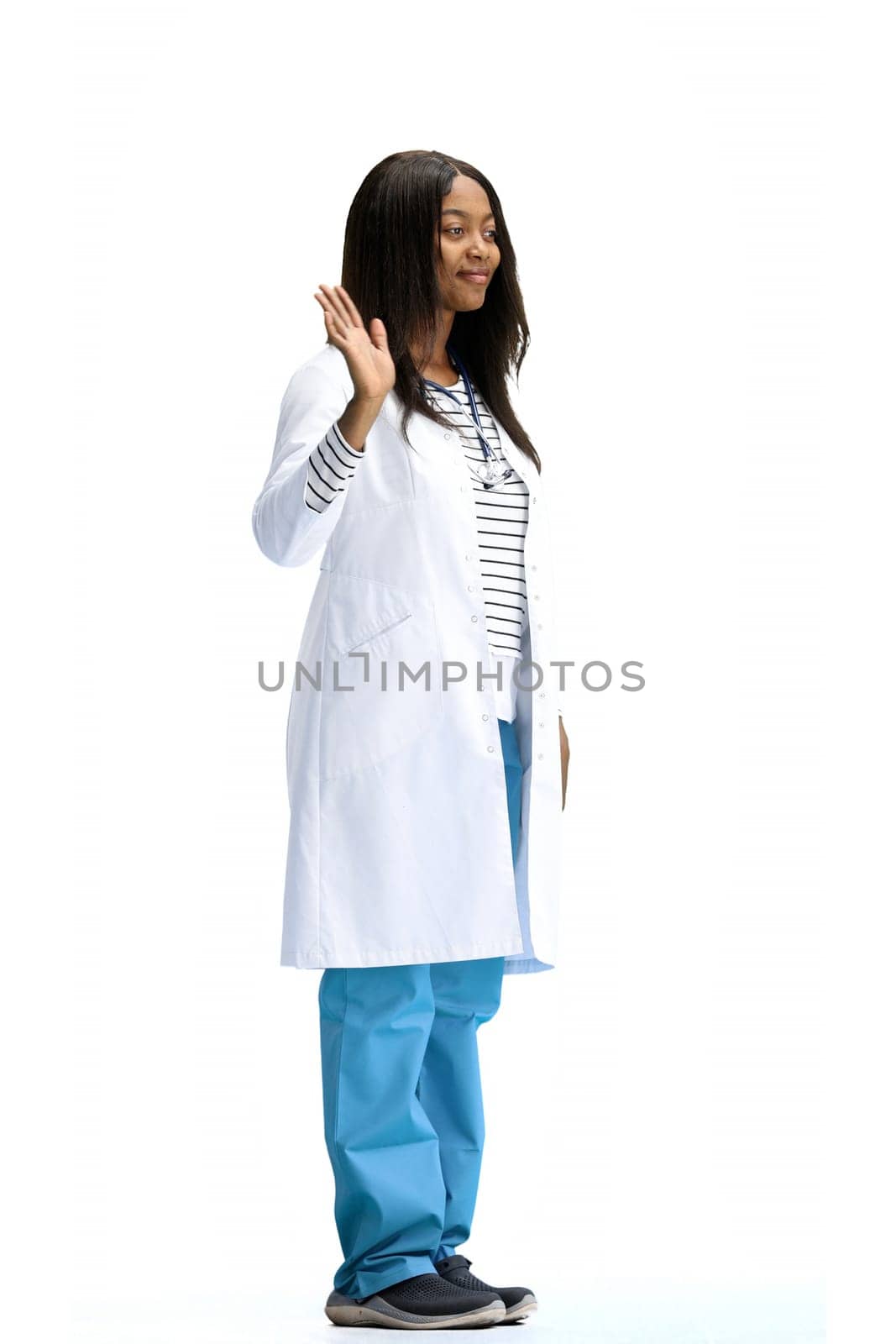 A female doctor, on a white background, in full height, waving her hand.