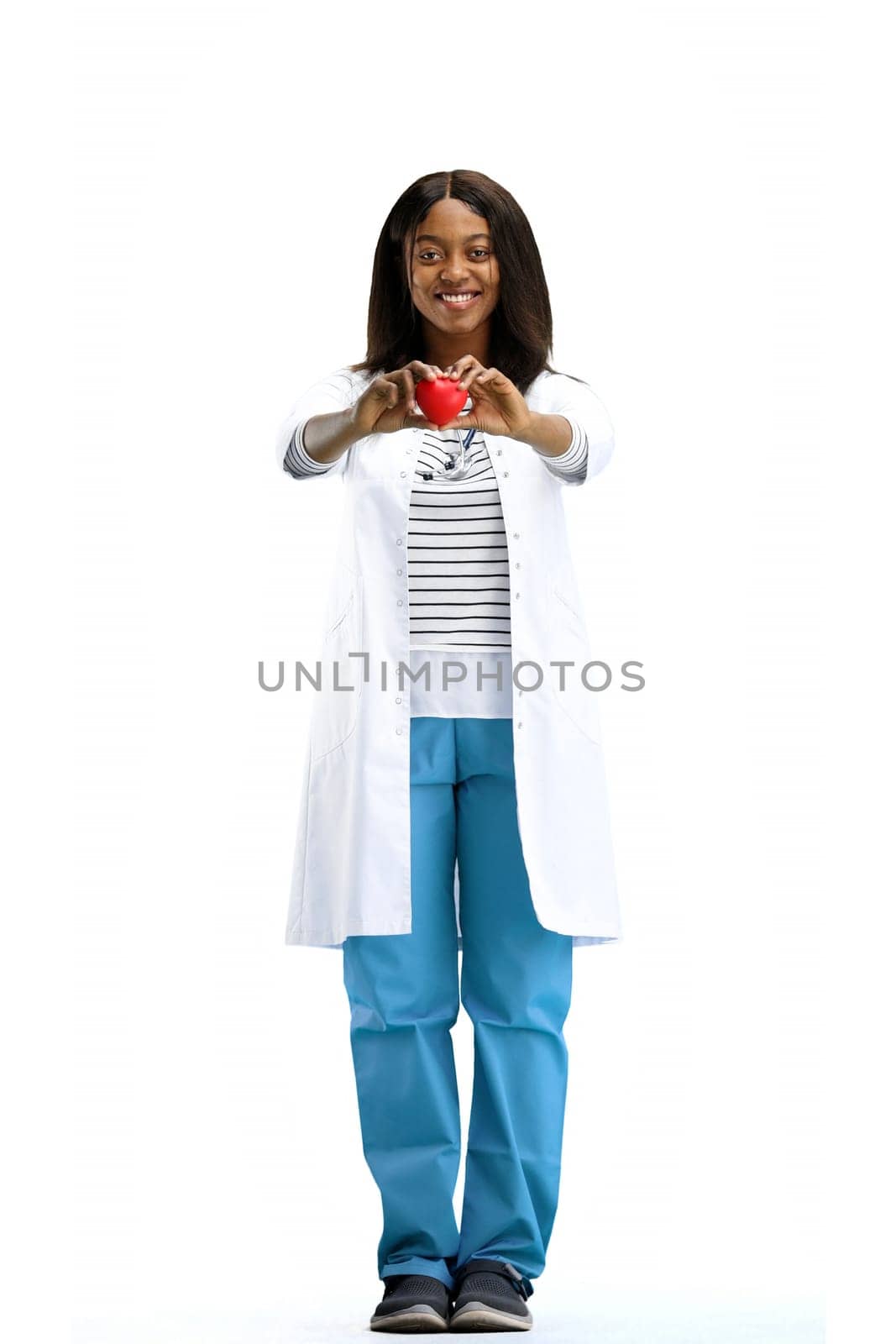A female doctor, full-length, on a white background, shows a heart.