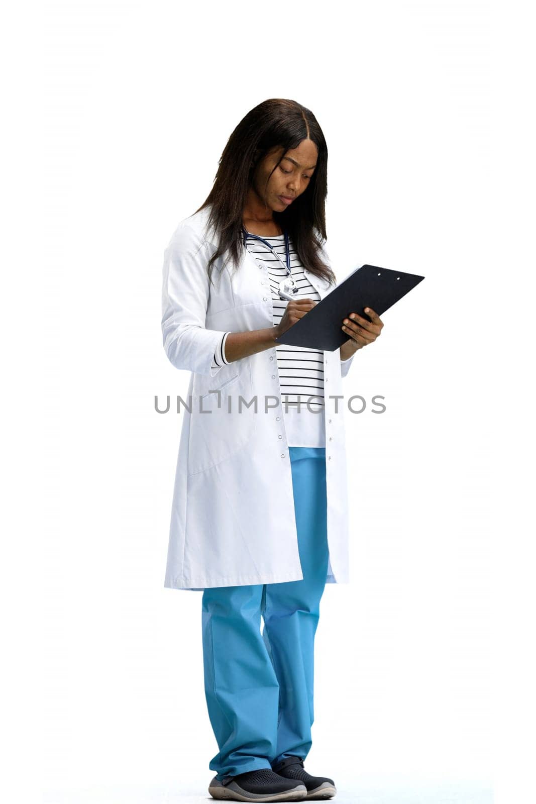 A woman doctor, full-length, on a white background, writes.