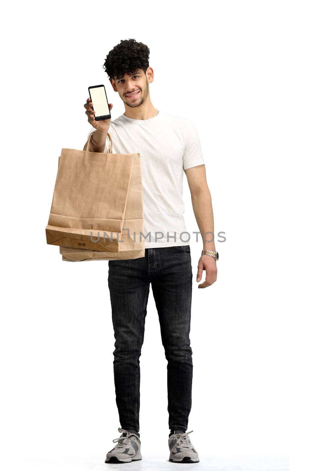 A man, on a white background, in full height, with bags and a phone.