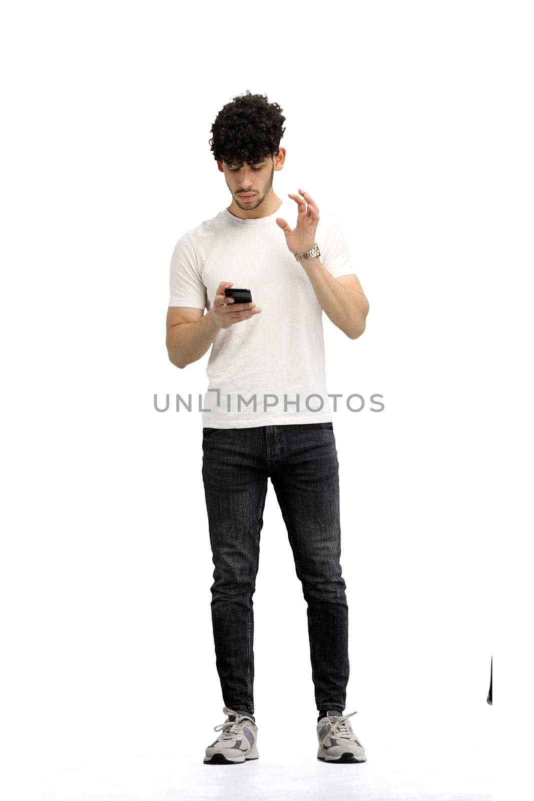 A man, on a white background, in full height, with bags and a phone.