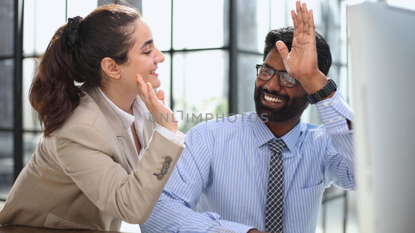 Happy businesswoman using laptop while working with colleague in the office. high five