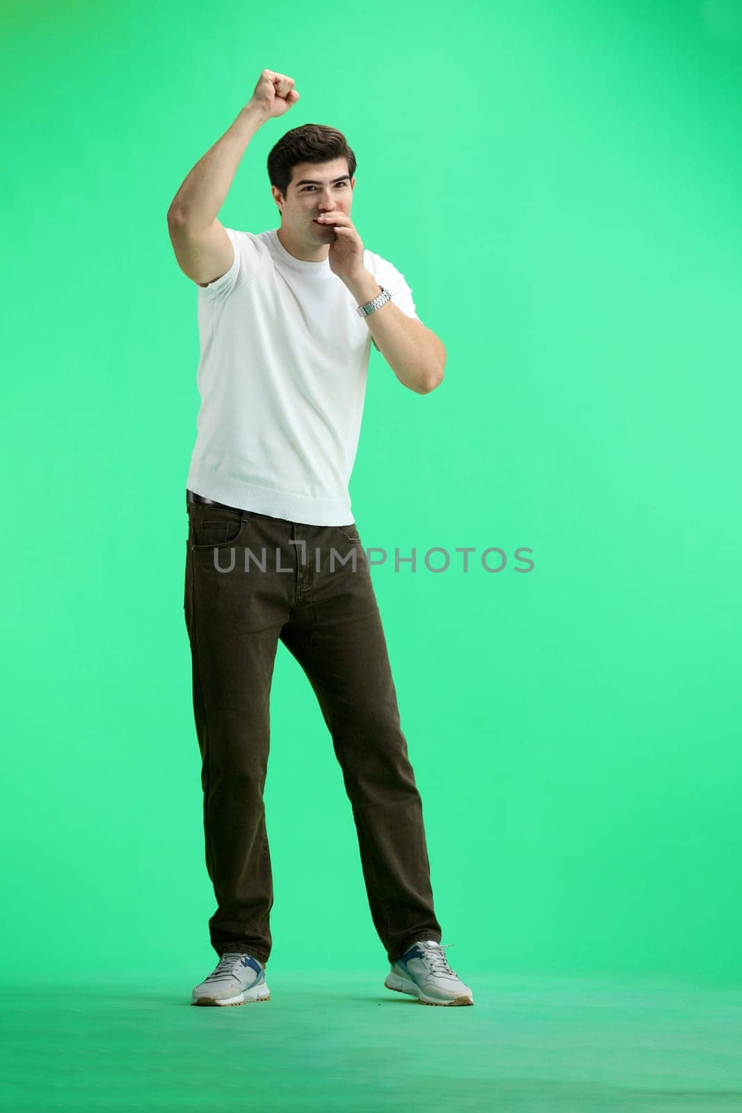 A man in full height, on a green background, rejoices.