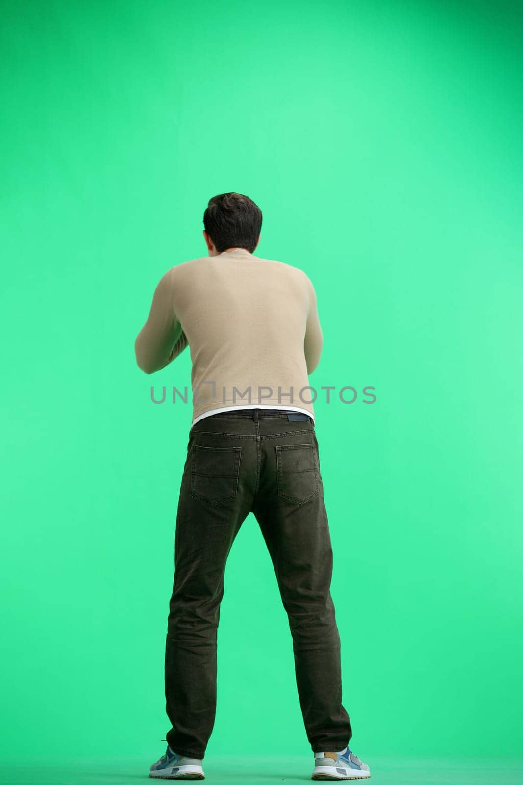 A man, full-length, on a green background, screams.
