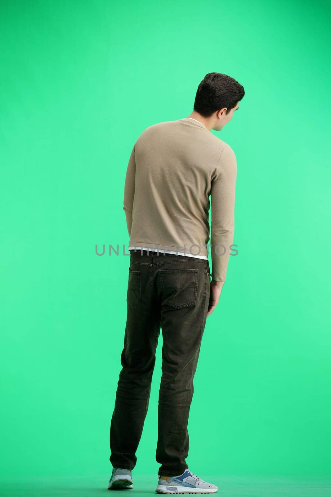 A man, full-length, on a green background.