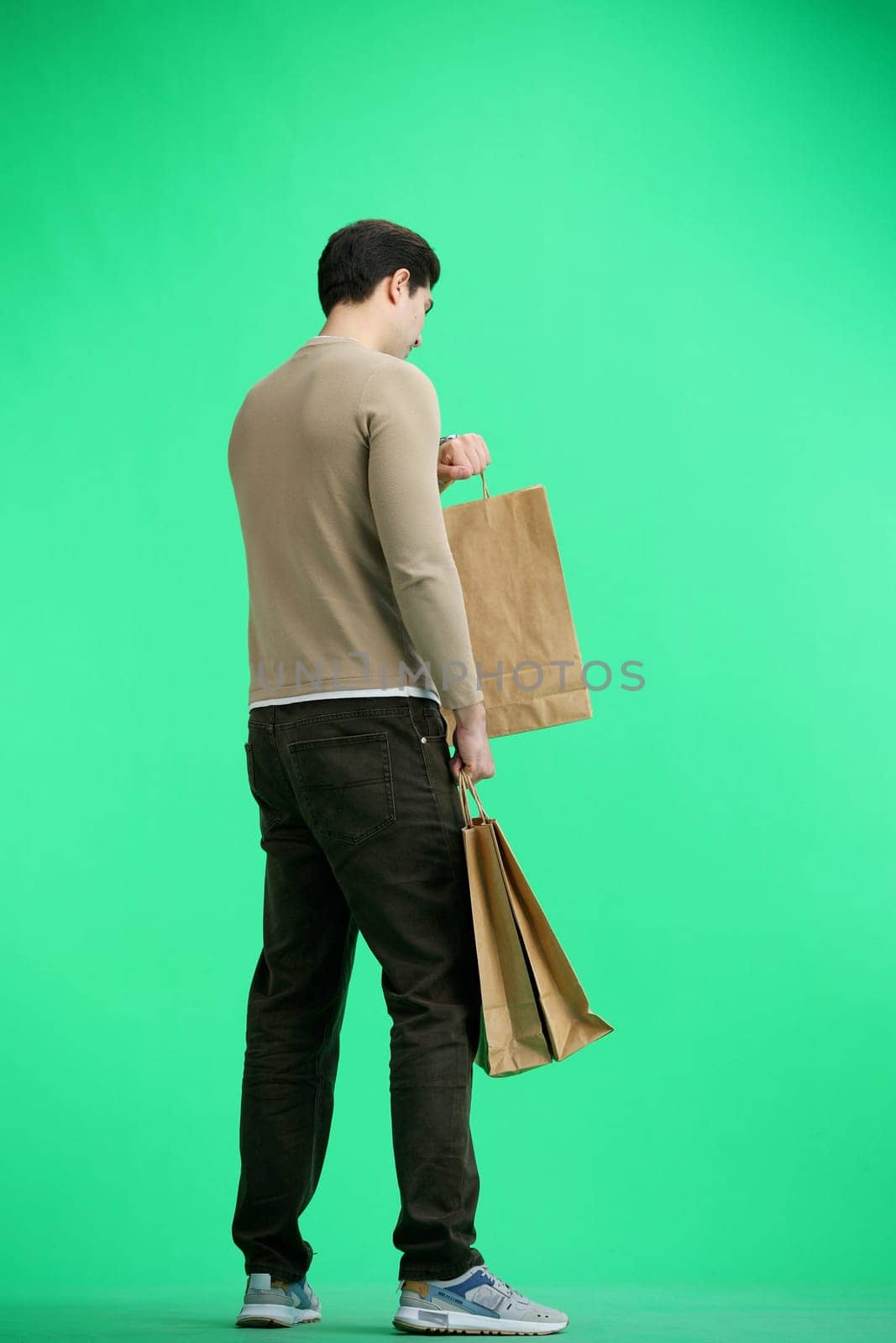 A man, full-length, on a green background, in packages by Prosto