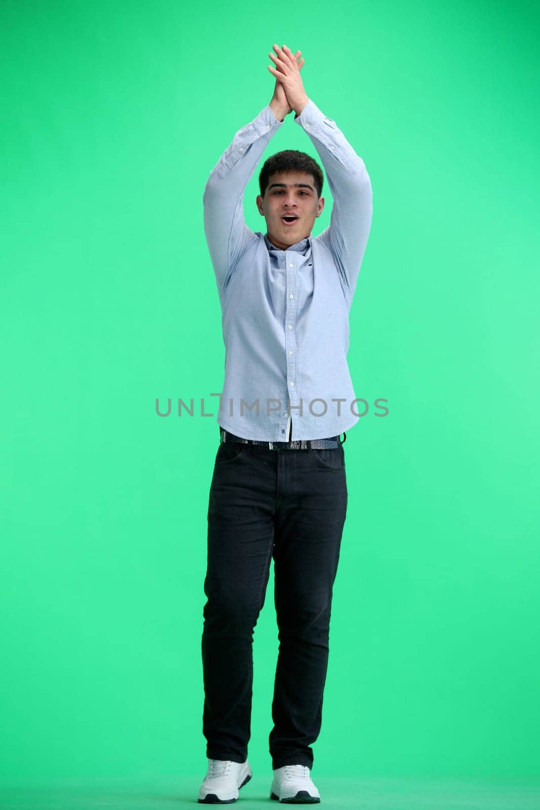 A man, full-length, on a green background, claps.