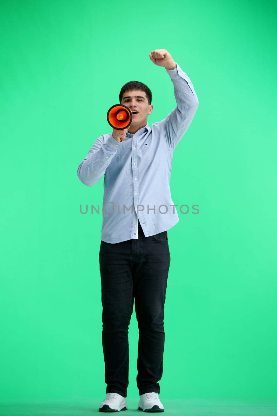 A man, full-length, on a green background, with a megaphone by Prosto