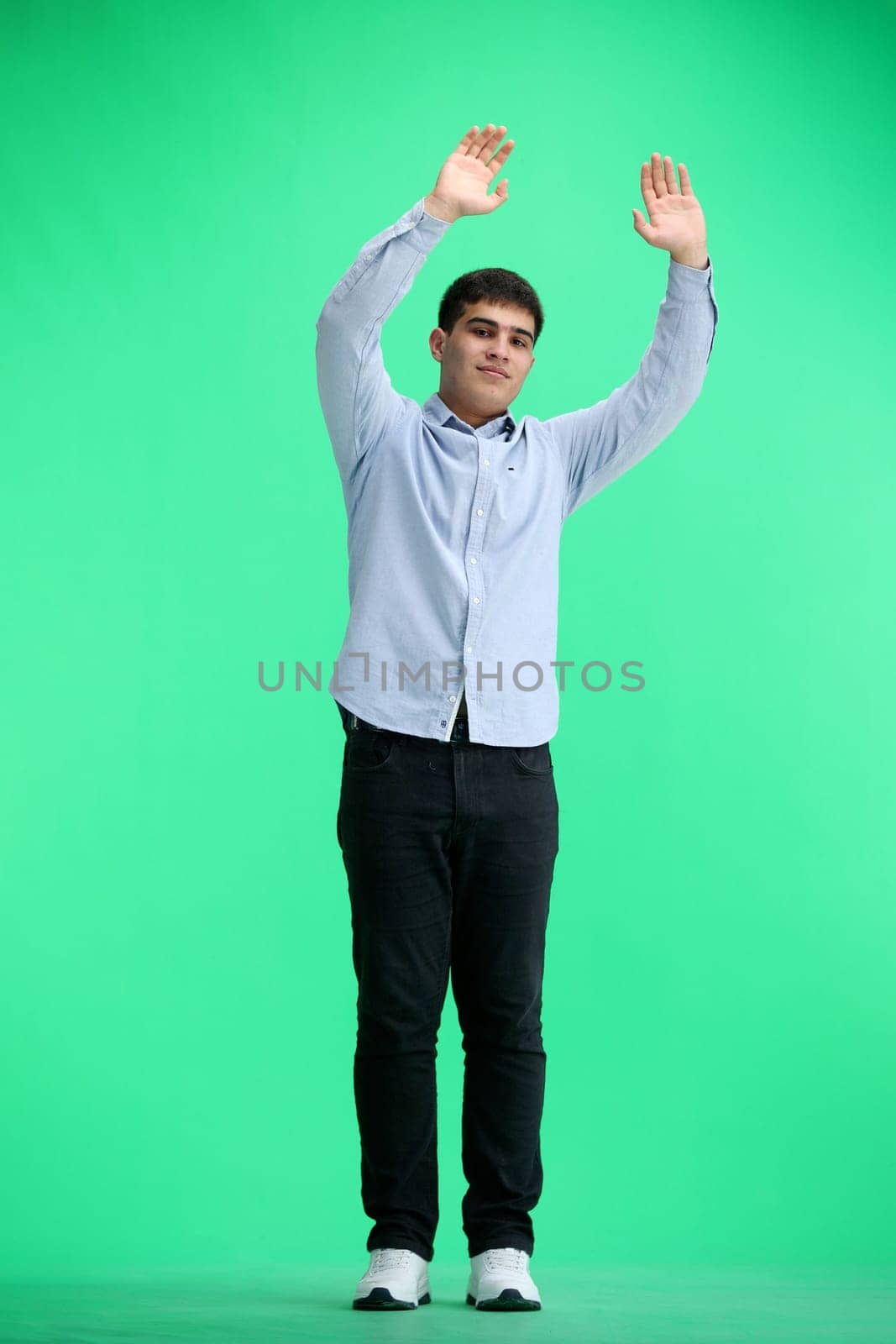 A man, full-length, on a green background, waving his arms.