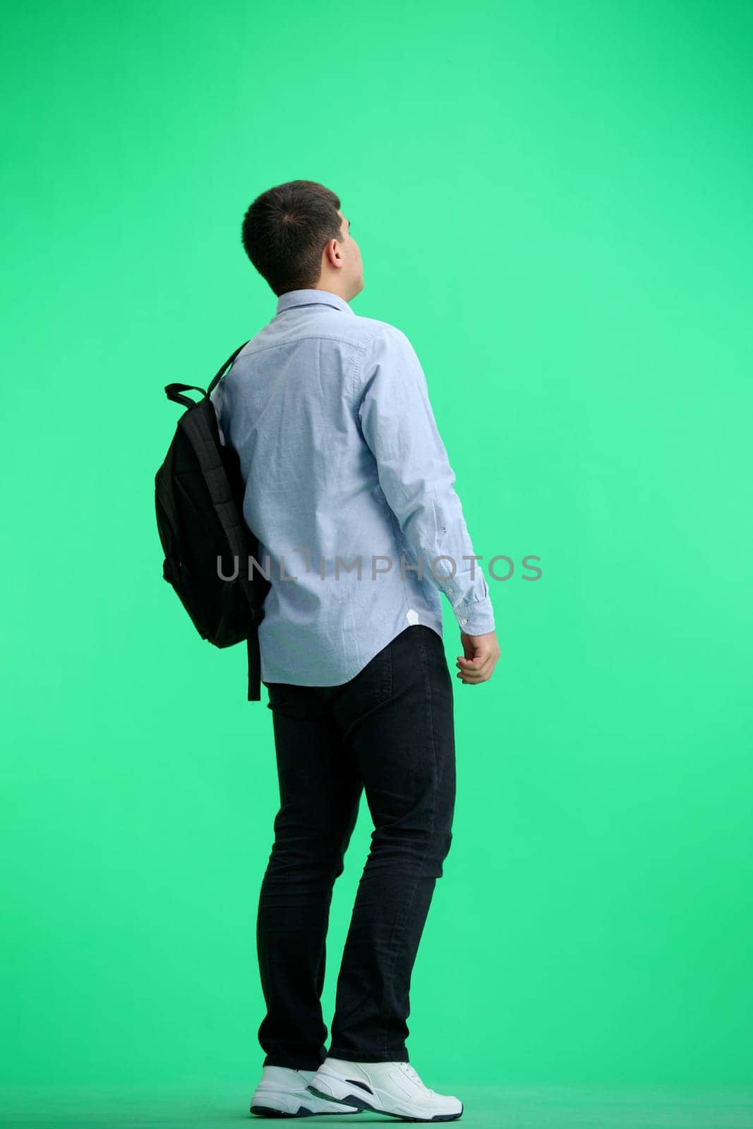 A man, full-length, on a green background, with a briefcase.