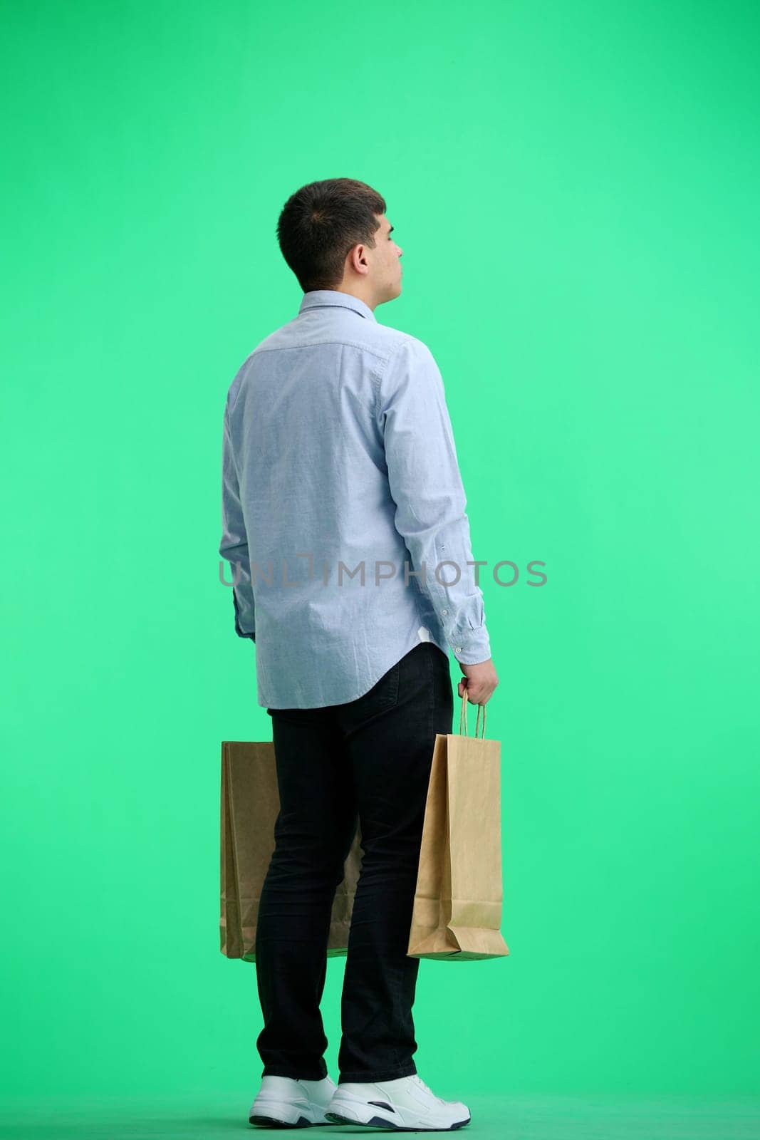 A man, full-length, on a green background, with bags by Prosto