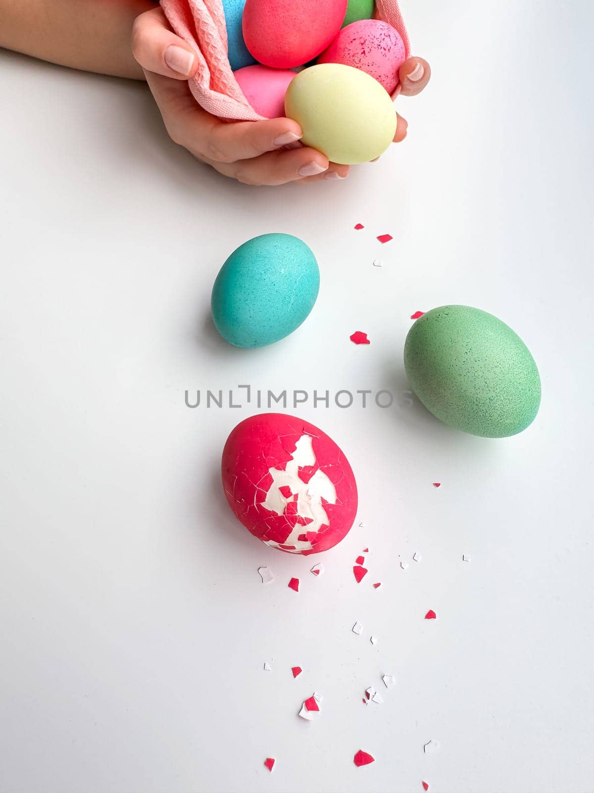 Hands holding colorful painted Easter eggs with one cracked egg on the side, representing Easter festivities, spring celebrations, and family fun activities. by Lunnica