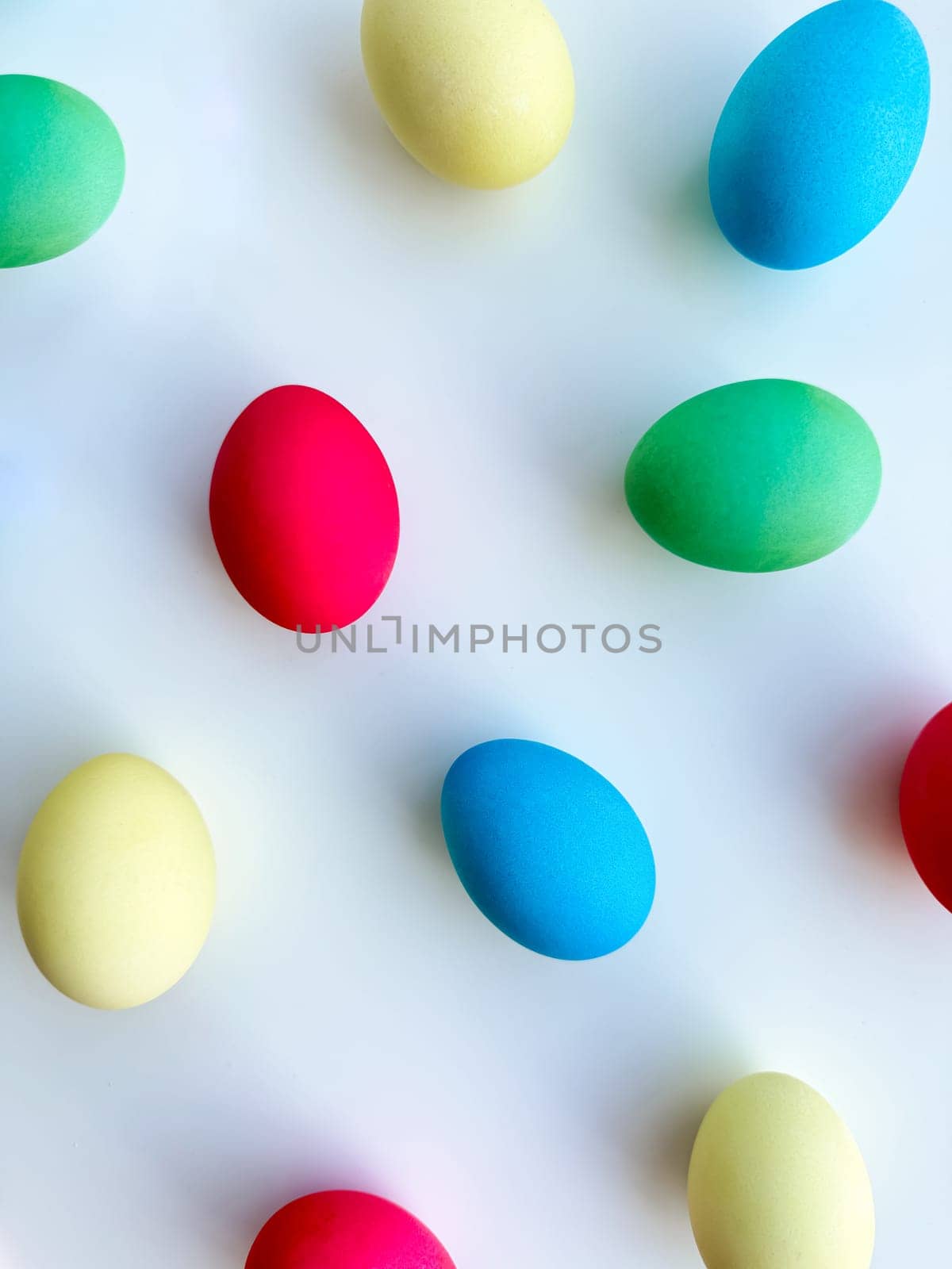 Colorful Easter eggs scattered on white background, flat lay composition for spring holiday celebration and decoration ideas. For Easter holiday promotions, themed party invitations, seasonal blog posts, educational materials about Easter, background imagery for websites and social media platforms celebrating the spring season. High quality photo