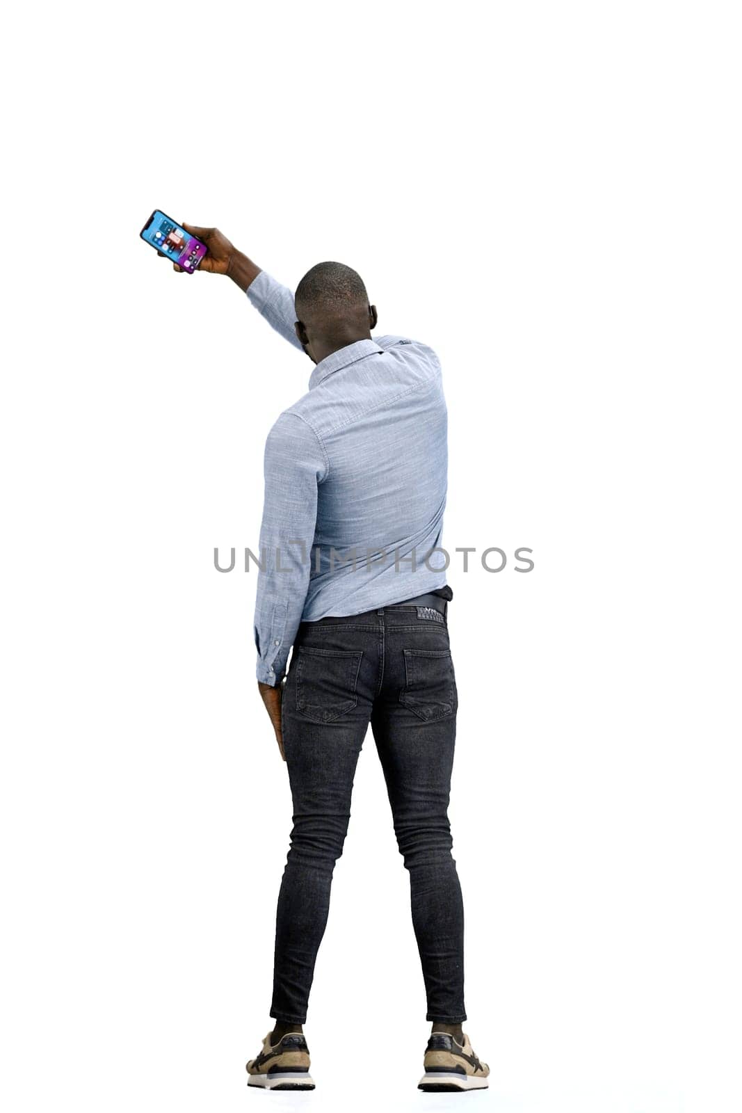 A man, full-length, on a white background, waving his phone.
