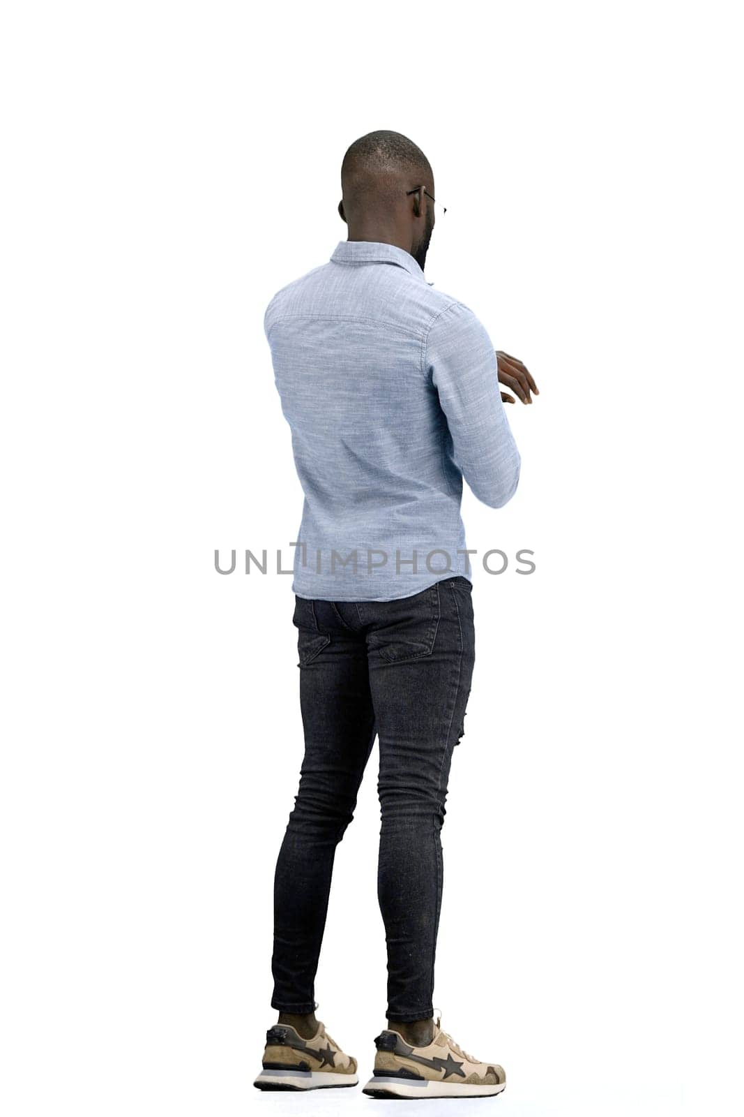 A man, full-length, on a white background, looks at his watch.