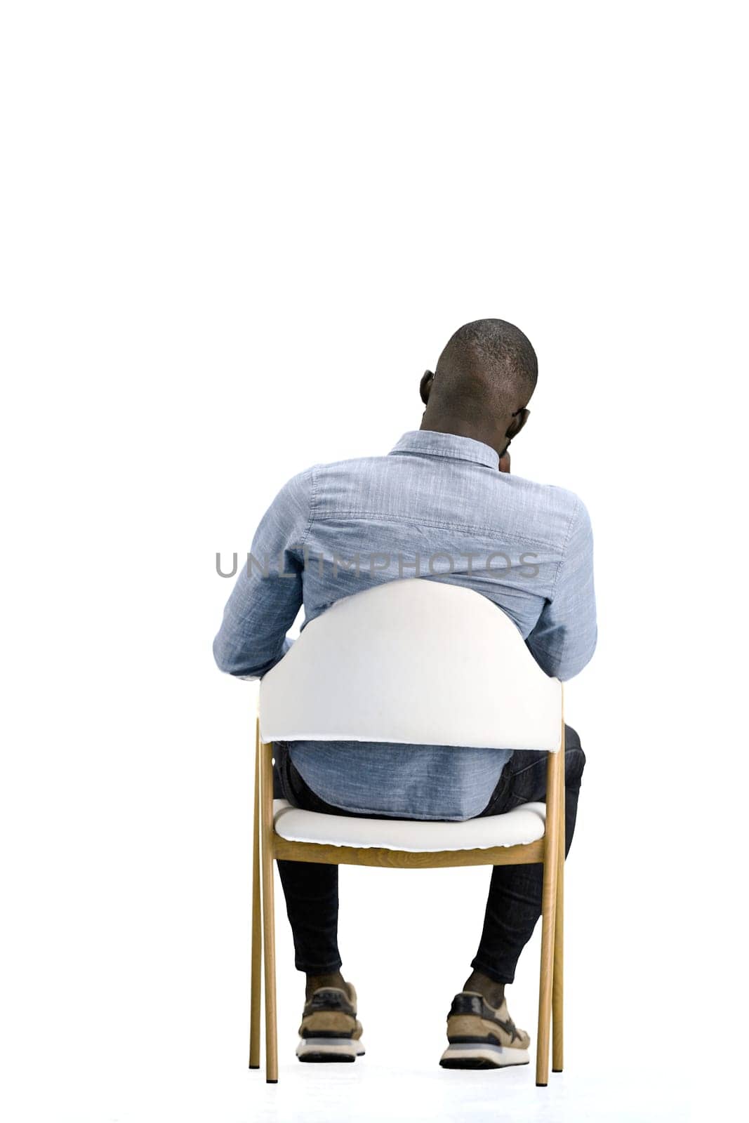 A man, on a white background, sitting on a chair.