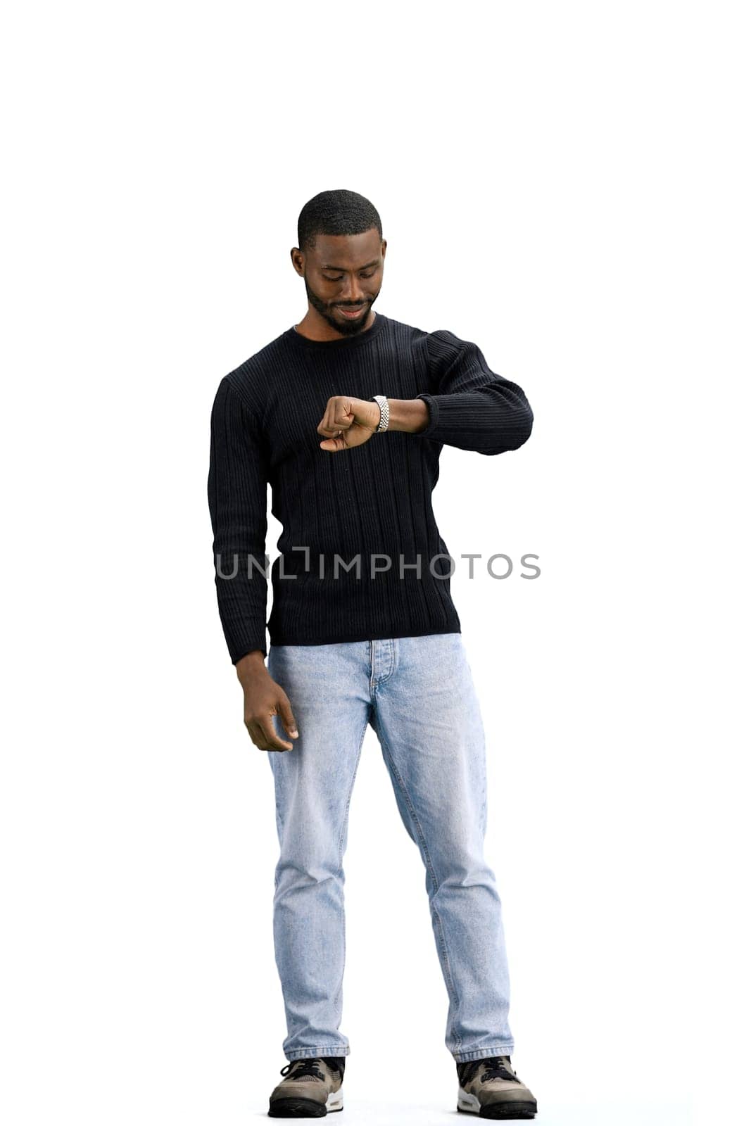 A man, full-length, on a white background, looks at his watch.