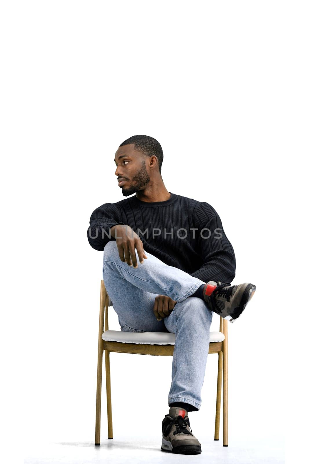 A man, on a white background, sitting on a chair.