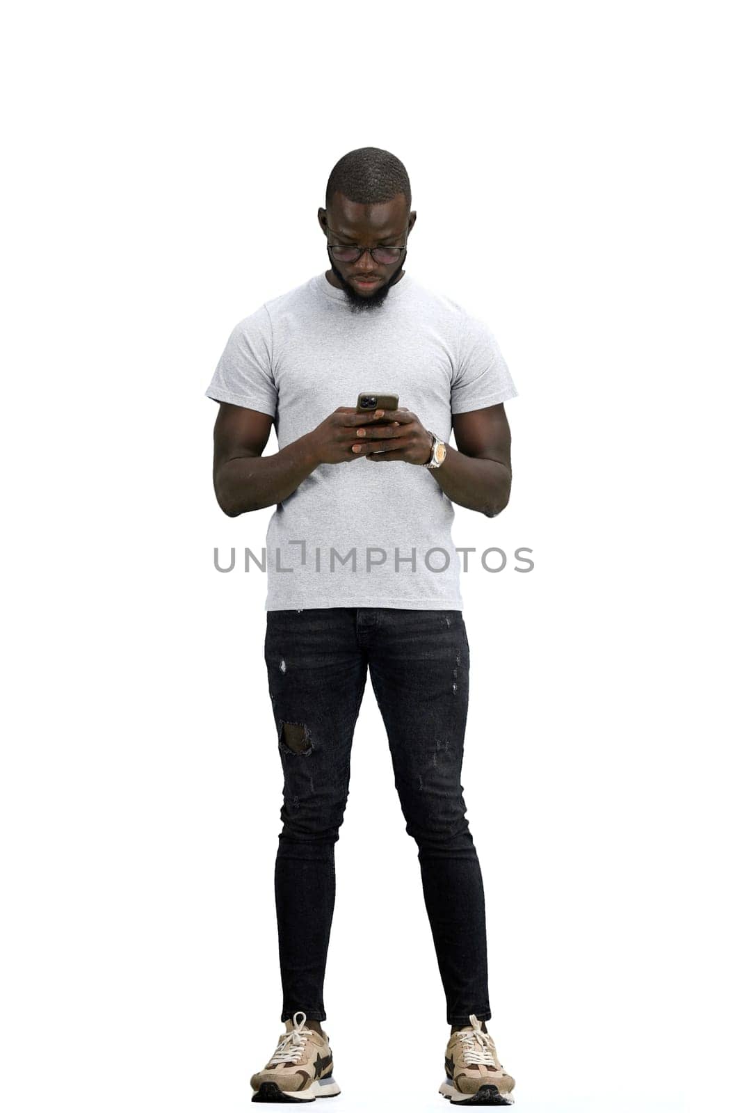 A man, full-length, on a white background, uses a phone.