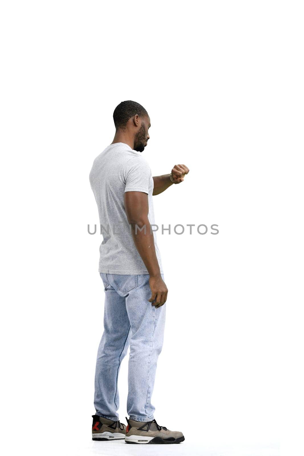 A man, full-length, on a white background, looks at his watch.