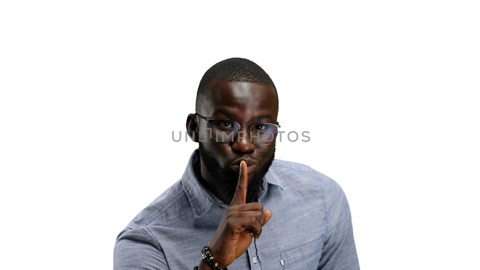 A man, close-up, on a white background, shows a sign of silence.