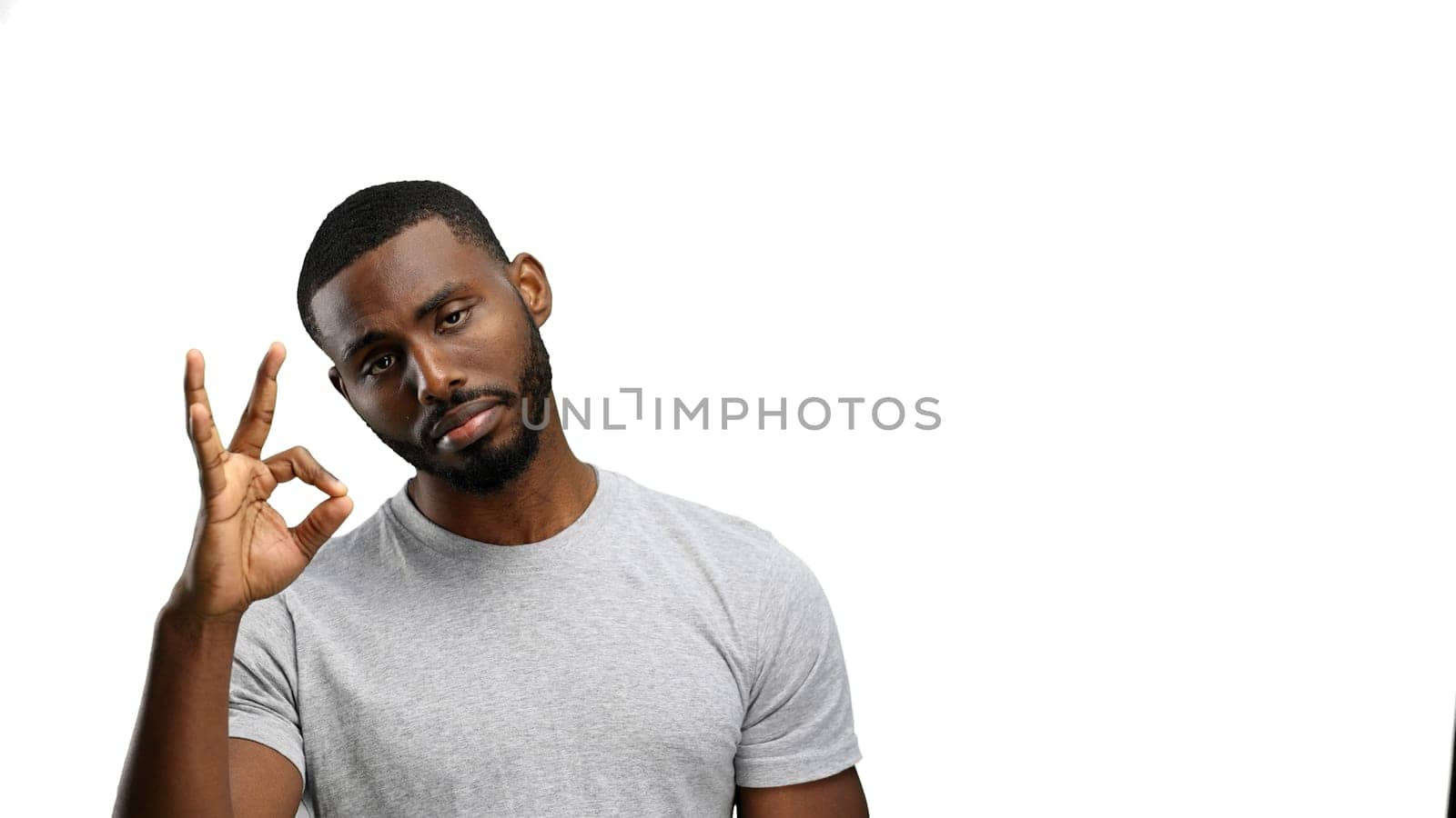 A man, close-up, on a white background, shows an ok sign.