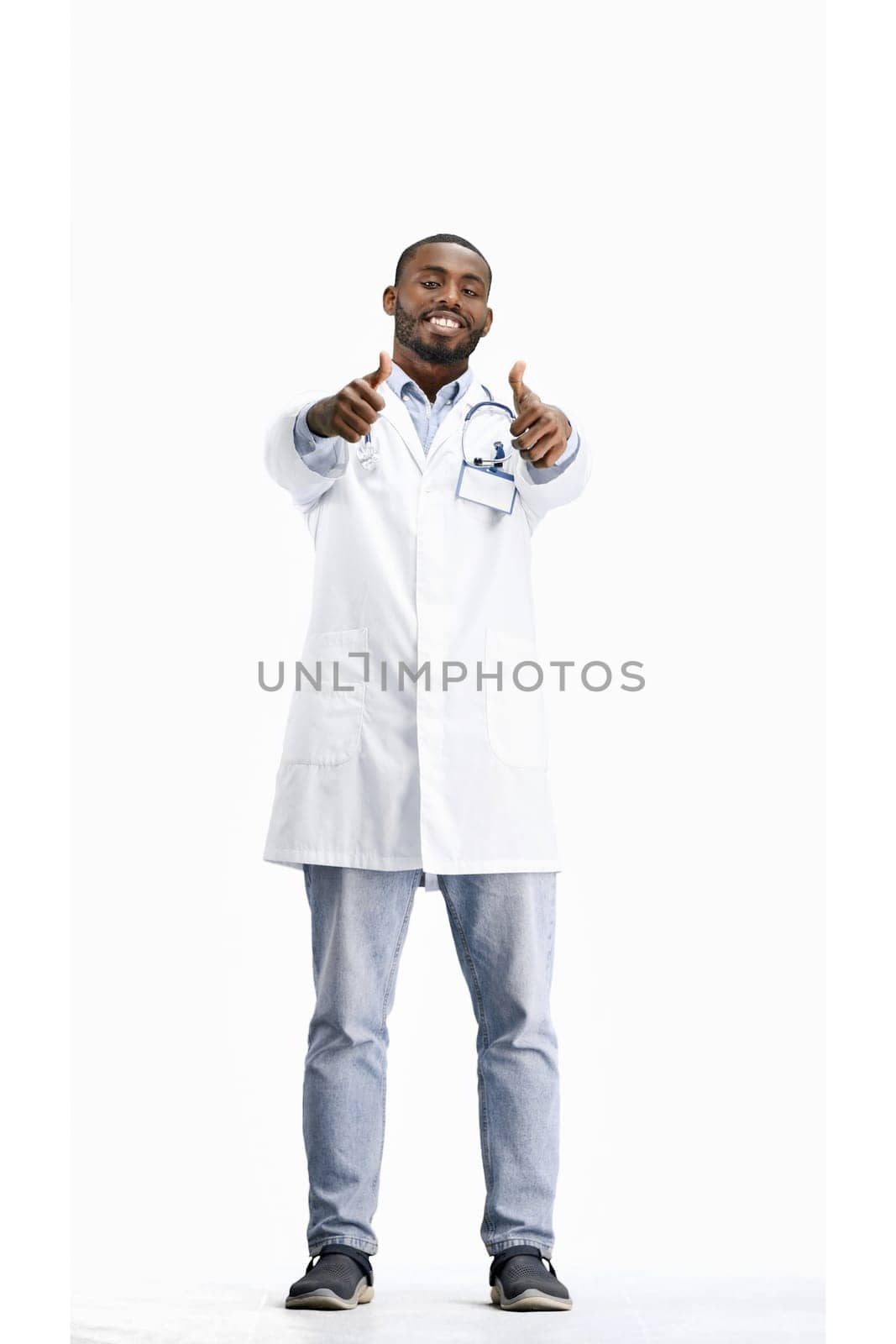 The doctor, in full height, on a white background, shows his thumbs up.