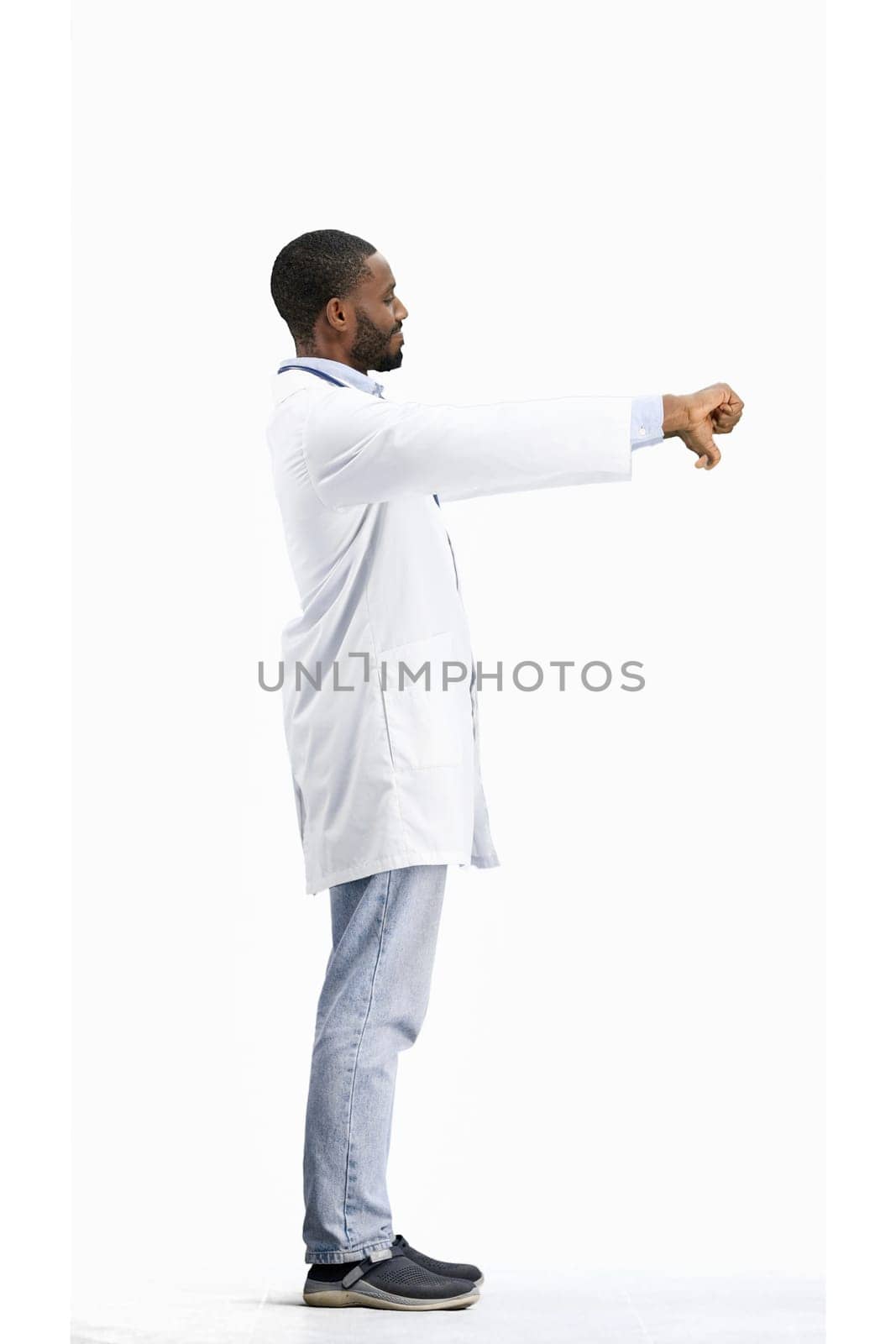 The doctor, in full height, on a white background, shows his thumbs down by Prosto