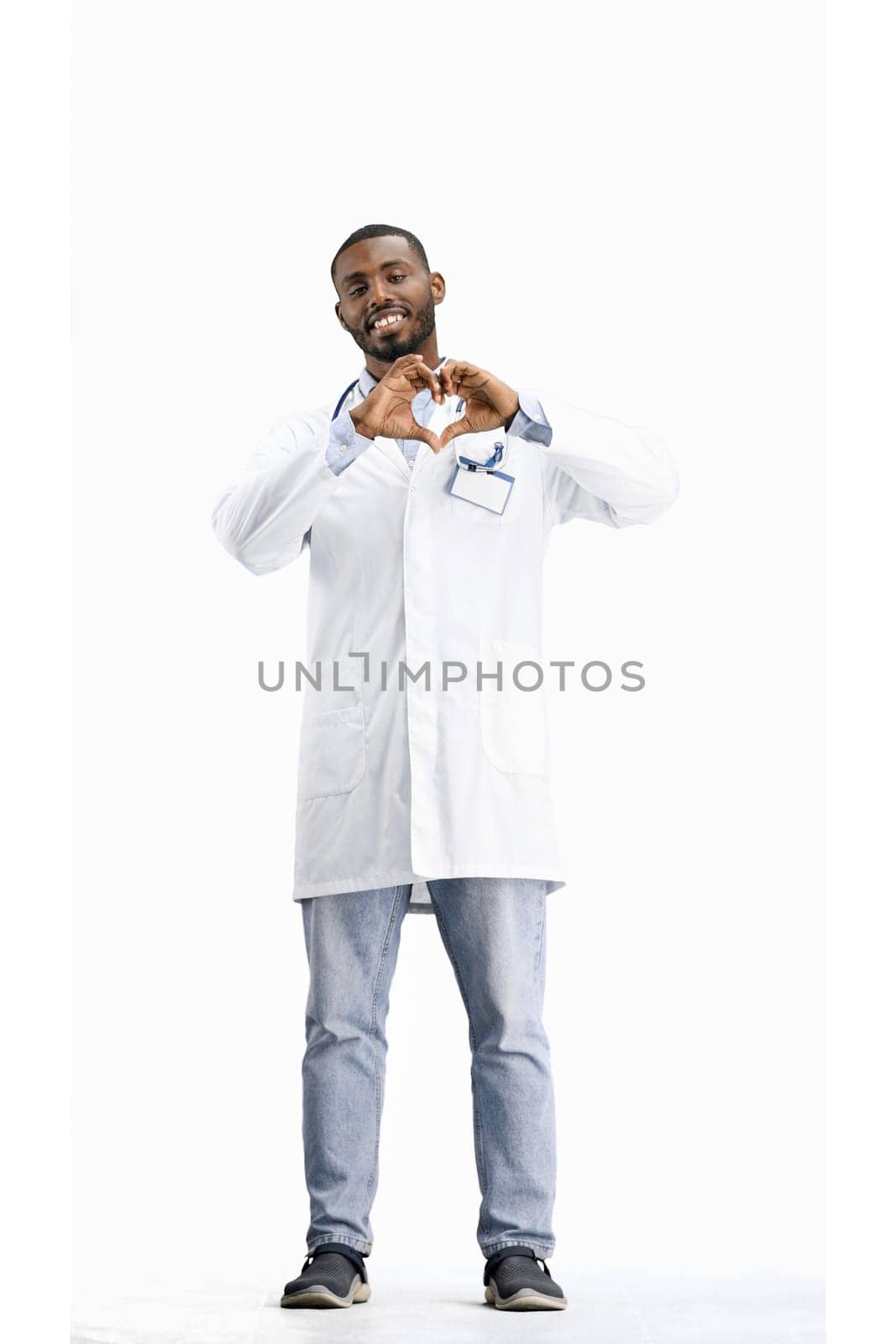 The doctor, in full height, on a white background, shows the heart.