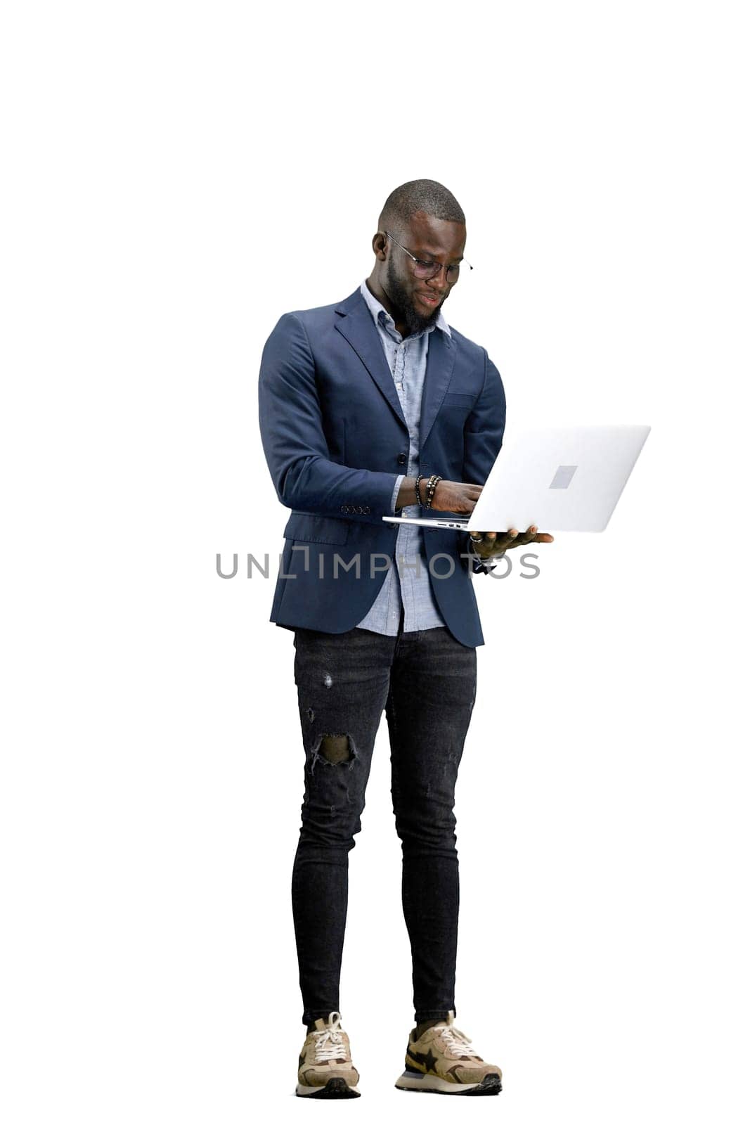 A man, full-length, on a white background, uses a laptop.