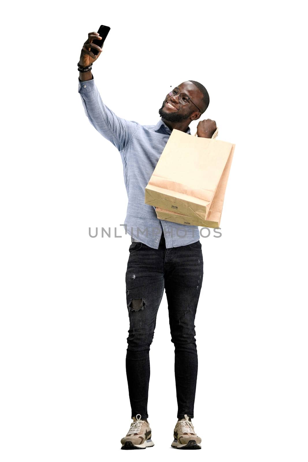 A man, full-length, on a white background, with bags and a phone.