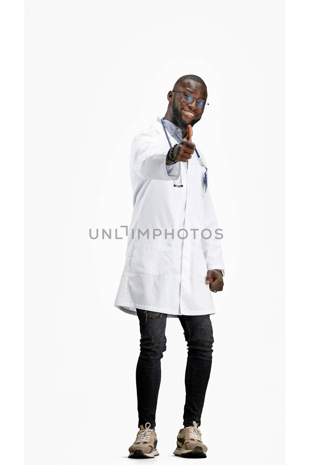 The doctor, in full height, on a white background, shows a thumbs up.