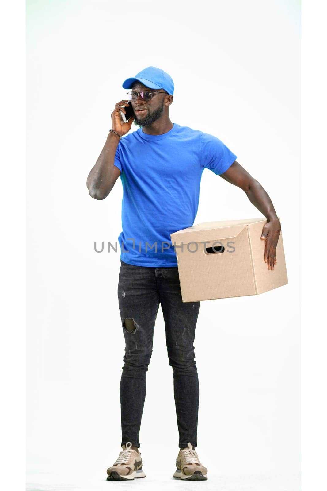 The deliveryman, in full height, on a white background, talking on the phone.