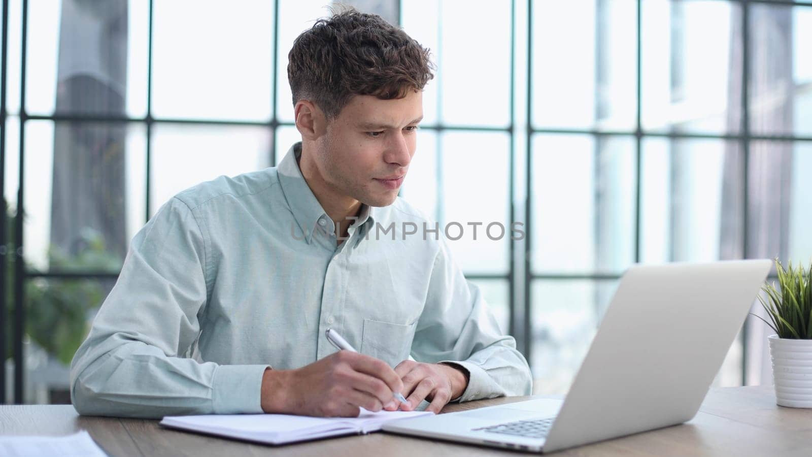 Shot of a young businessman using a laptop in a modern office by Prosto