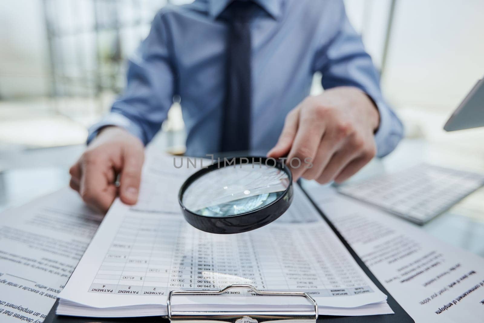 man looking through a magnifying glass to documents notebook.