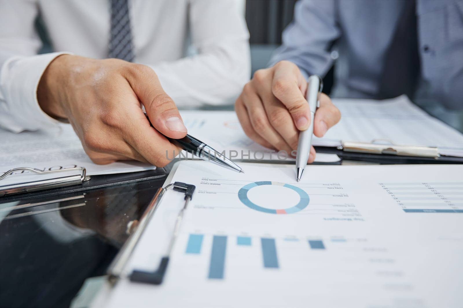 hand of a businessman shows a close-up index on the growth charts profit on the background of business documents and graphics