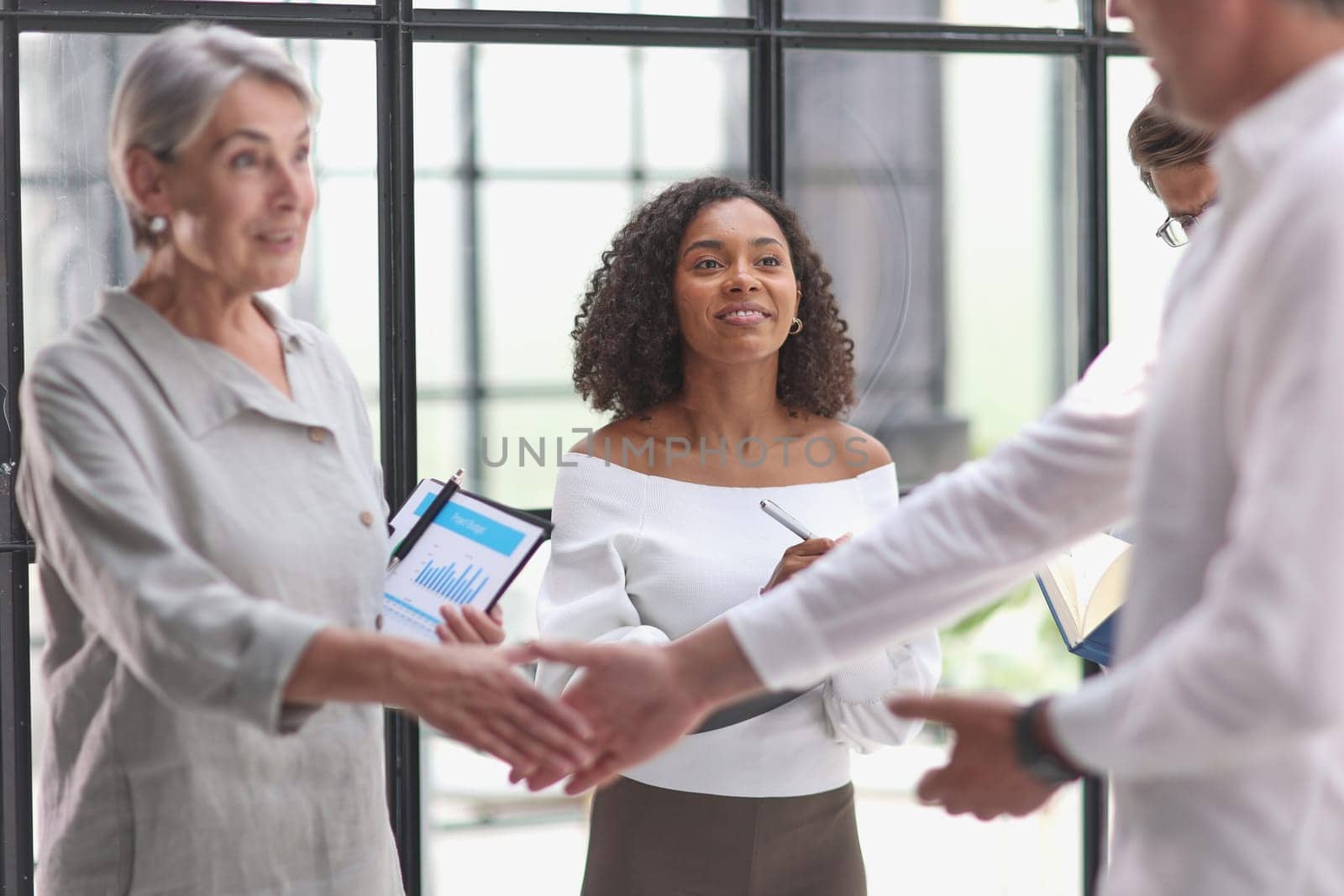 Group of business workers standing together shaking hands at the office by Prosto